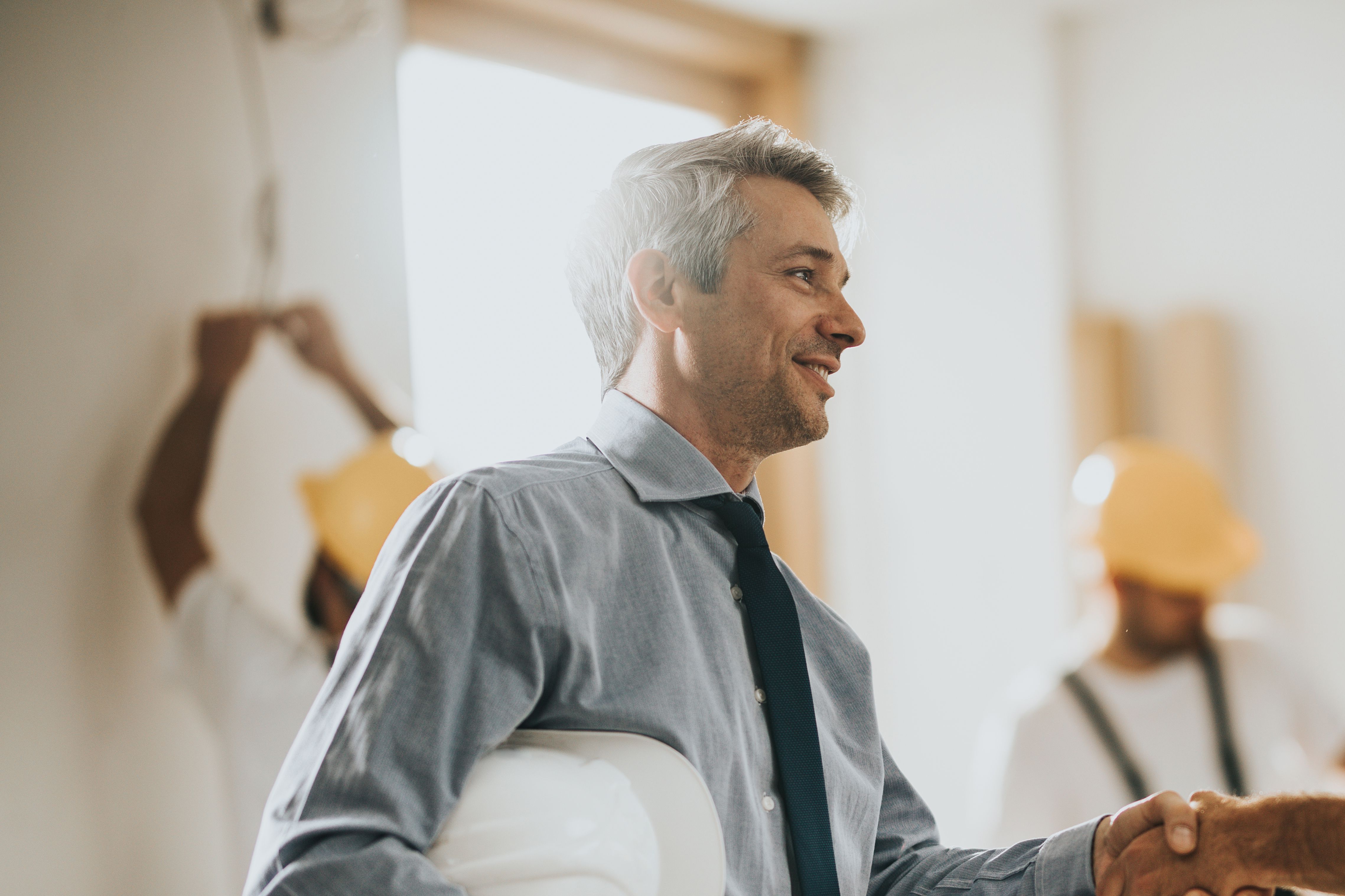 Happy construction worker greeting mid adult foreman at renovating apartment.