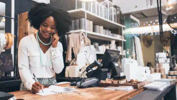 Woman talks on phone and writes in ledger