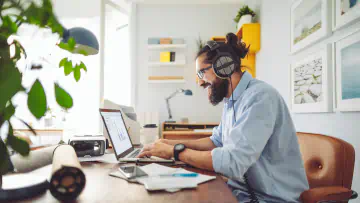 Man sits at desk, uses laptop