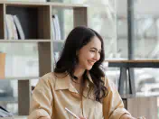 Woman uses a computer and takes notes