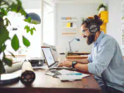 Man sits at desk, uses laptop